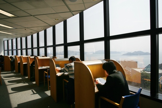 library shot of students studying and the windows of the library overlooking the ocean