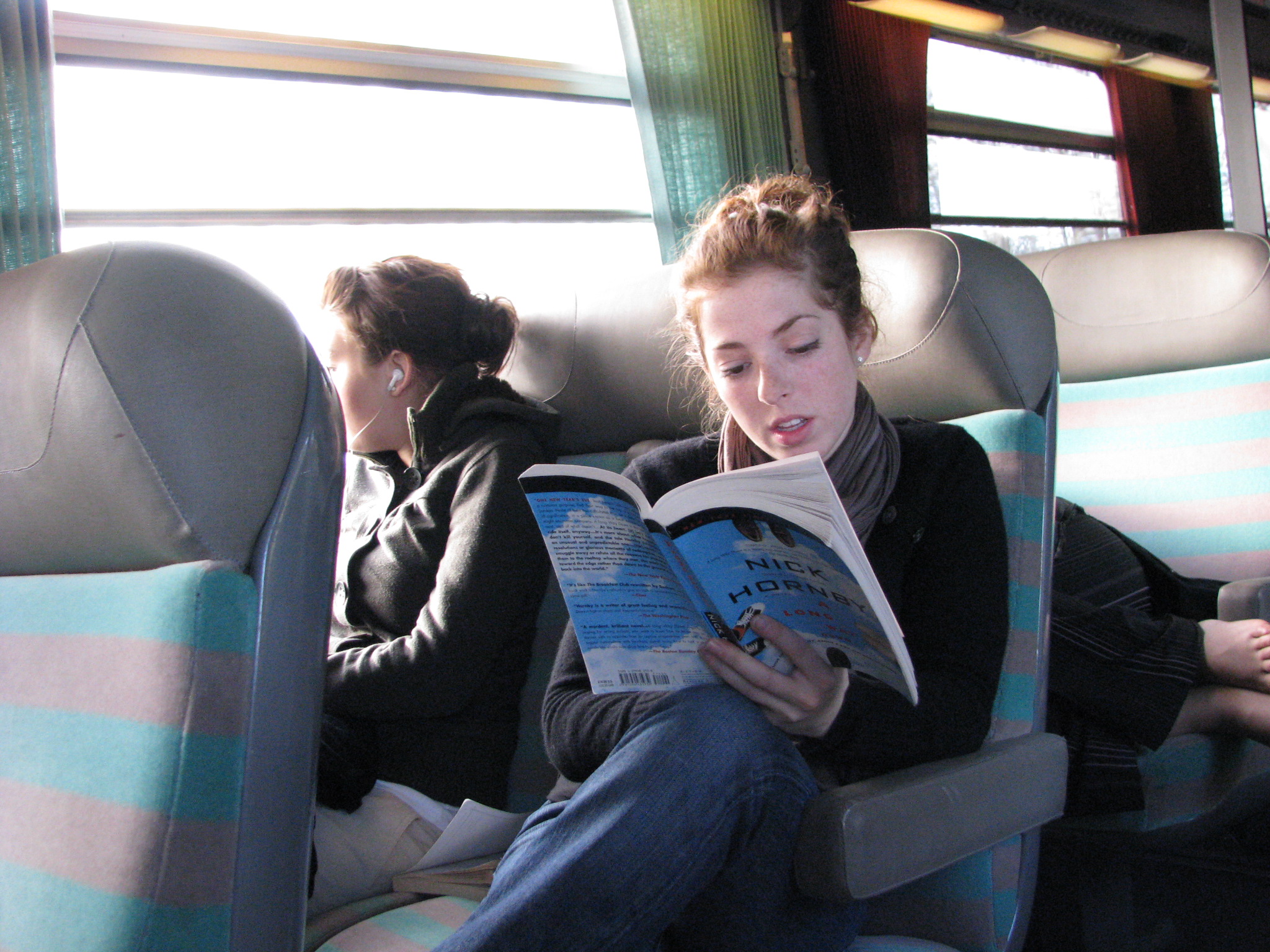 two students on a train, one looking out the window, the other consulting a guidebook