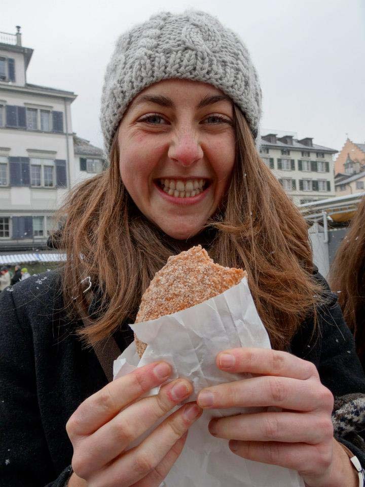 student smiling while holding a pastry